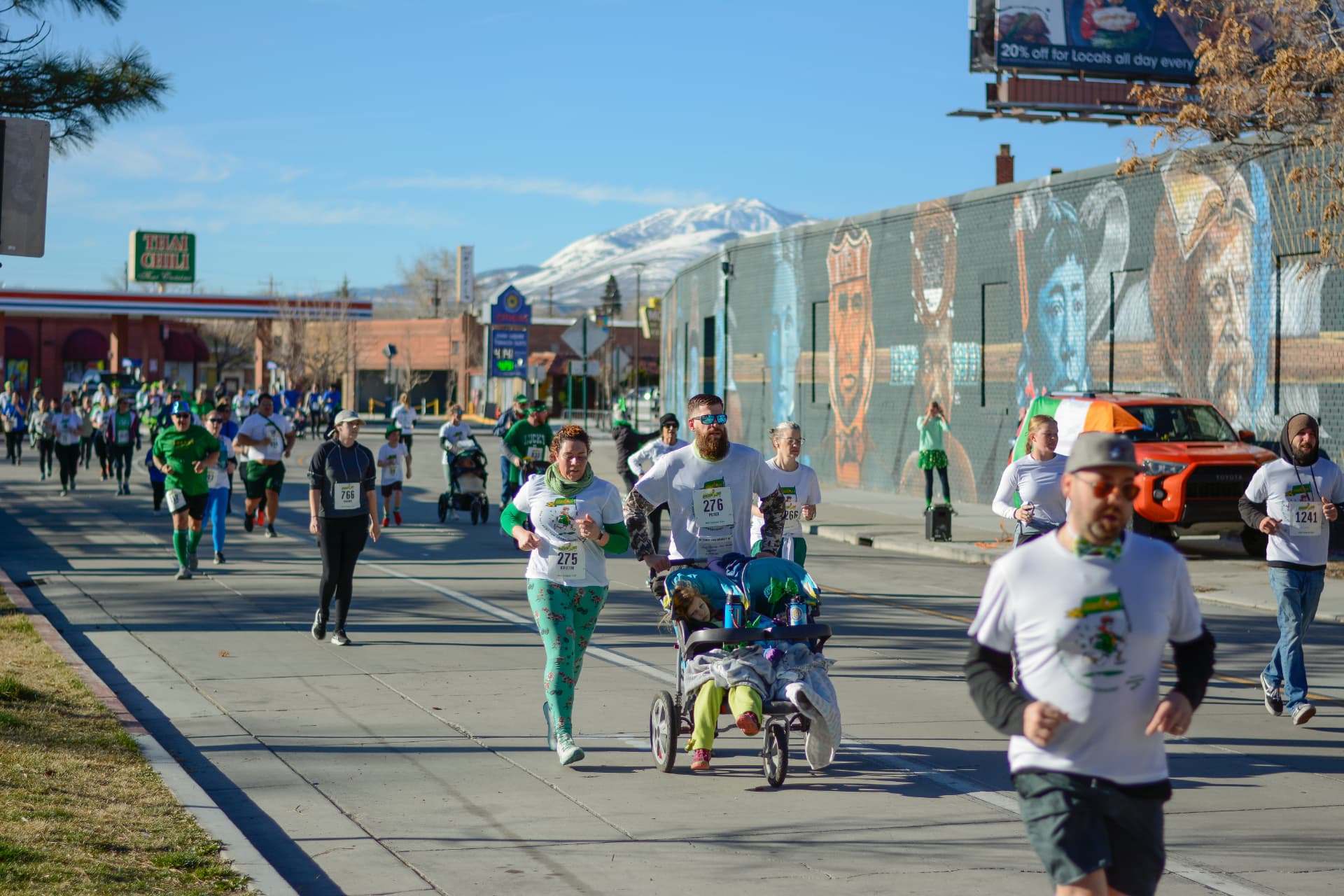 A family cruising past the mural wall with a stroller in tow